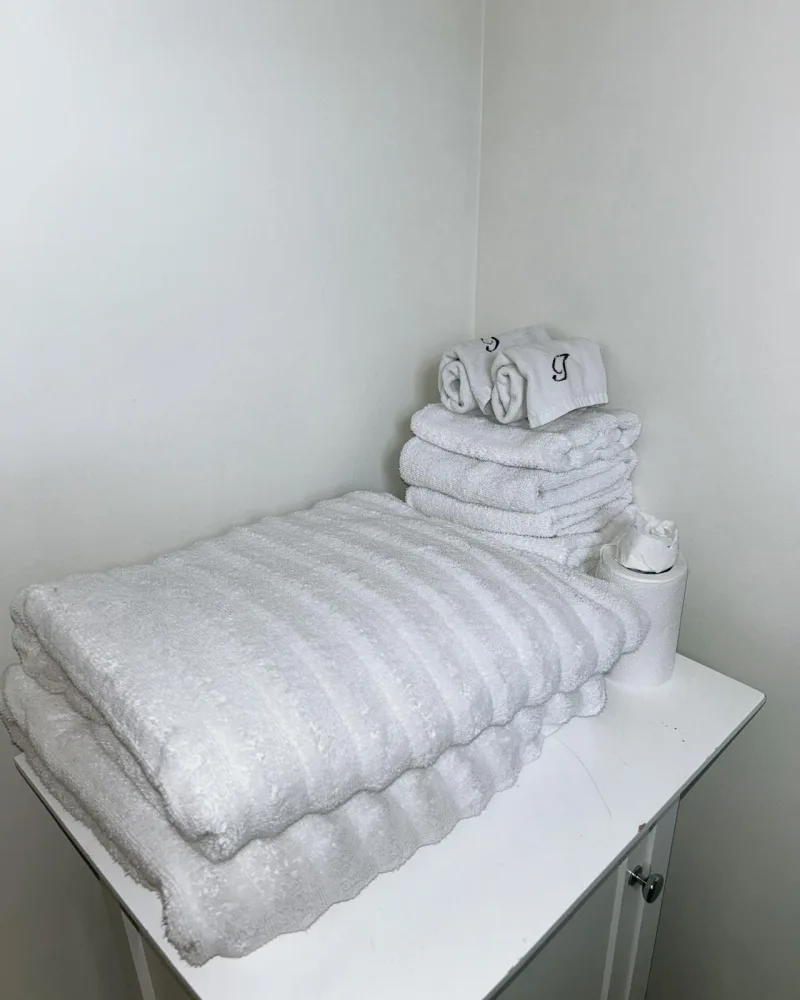 Neatly folded white towels stacked on a bathroom cabinet